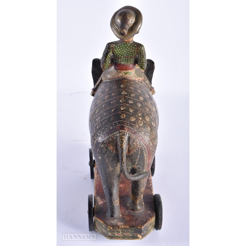 99 - AN ANTIQUE INDIAN PAINTED WOOD TOY modelled as an elephant with attendant. 27cm x 18cm.