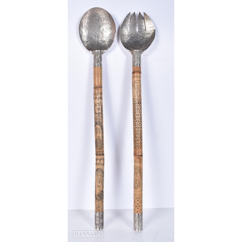 3012 - A pair of carved bamboo and engraved white metal  salad servers decorated with South East Asian char... 