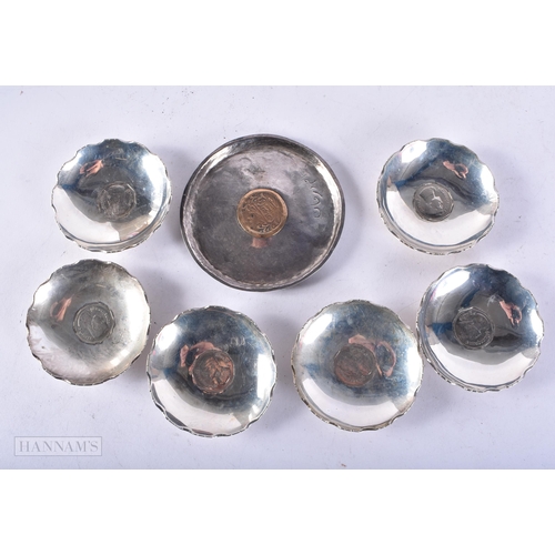 4097 - AN ISLAMIC WHITE METAL COIN INSET DISH together with six other dishes inset with Thai coins. 256 gra... 