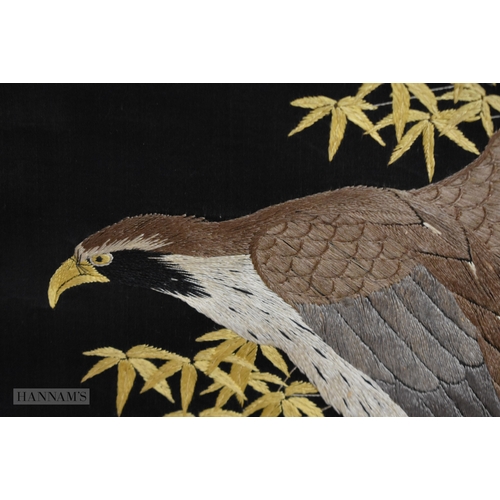 150 - A 19TH CENTURY JAPANESE MEIJI PERIOD BLACK EMBROIDERED SILK SCROLL decorated with a hawk amongst fol... 