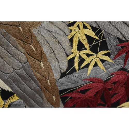 150 - A 19TH CENTURY JAPANESE MEIJI PERIOD BLACK EMBROIDERED SILK SCROLL decorated with a hawk amongst fol... 