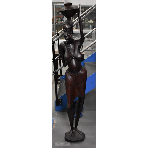 374 - A LARGE MID CENTURY CARVED HARDWOOD FIGURE OF AN AFRICAN FEMALE modelled as a water carrier. 162 cm ... 