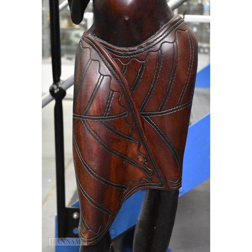 374 - A LARGE MID CENTURY CARVED HARDWOOD FIGURE OF AN AFRICAN FEMALE modelled as a water carrier. 162 cm ... 