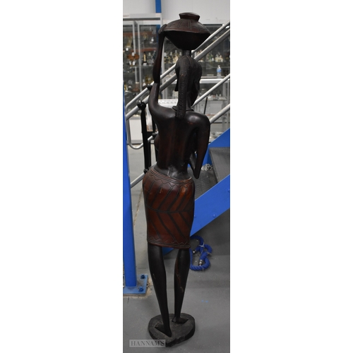 374 - A LARGE MID CENTURY CARVED HARDWOOD FIGURE OF AN AFRICAN FEMALE modelled as a water carrier. 162 cm ... 