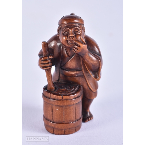 2058 - A JAPANESE CARVED WOOD NETSUKE formed as a male washing clothes. 5 cm x 2.75 cm.