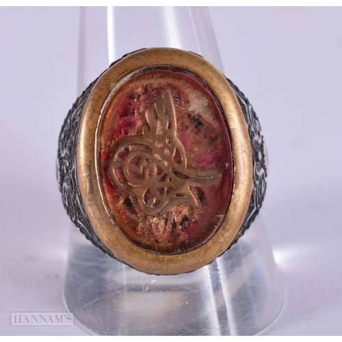 392 - AN UNUSUAL ANTIQUE ISLAMIC MIDDLE EASTERN SILVER ARABIC RING inset with a yellow metal glass cased m... 