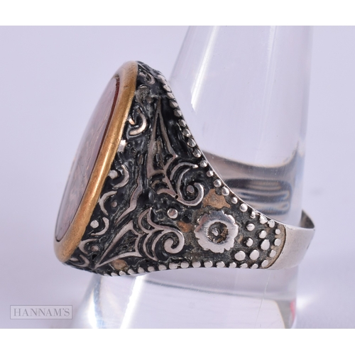 392 - AN UNUSUAL ANTIQUE ISLAMIC MIDDLE EASTERN SILVER ARABIC RING inset with a yellow metal glass cased m... 