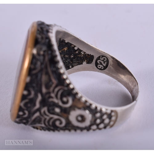 392 - AN UNUSUAL ANTIQUE ISLAMIC MIDDLE EASTERN SILVER ARABIC RING inset with a yellow metal glass cased m... 