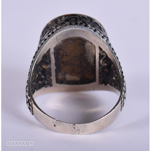 392 - AN UNUSUAL ANTIQUE ISLAMIC MIDDLE EASTERN SILVER ARABIC RING inset with a yellow metal glass cased m... 