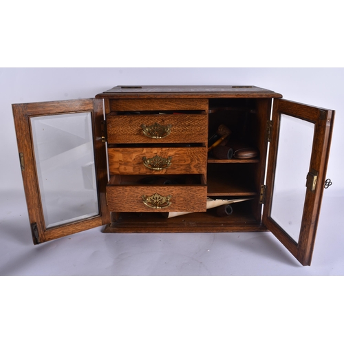47 - A LATE VICTORIAN/EDWARDIAN OAK SMOKERS CABINET containing pipes and matchbox cases, together with a ... 