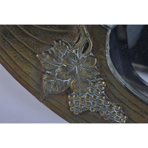 26 - A LARGE ARTS AND CRAFTS BRASS MIRROR overlaid with berries and vines. 86 cm x 68 cm.