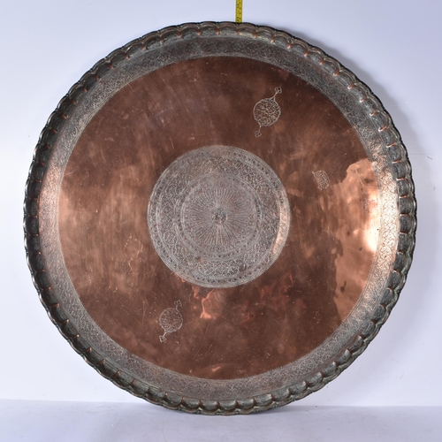 3191 - A large Middle eastern copper tray etched with Tugra and script and hammered scalloped rim 72 cm dia... 
