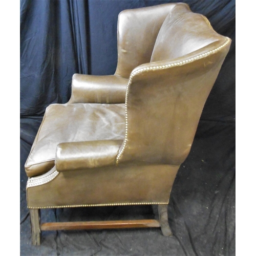 70 - LARGE LEATHER ARMCHAIR WITH BRASS STUD TO WING AND ARM (BASE STRETCHER COME AWAY BUT NOT BROKEN)