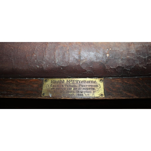 154 - OAK SLAT BACK BENCH WITH UPHOLSTERED SEAT (DAMAGED), BRASS PLAQUE - RHODD MRS TREHARNE EGLWYS PENWEL... 