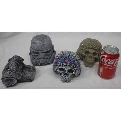 4 - 4 GARDEN ORNAMENTS - 2 SKULLS - 1 PAINTED, 1 BOXER DOG HEAD AND 1 STORM TROOPER HELMET