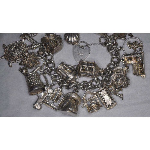 134 - SILVER CHARM BRACELET WITH 26 CHARMS AND HEART SHAPED LOCK AND SAFETY CHAIN 149.4g