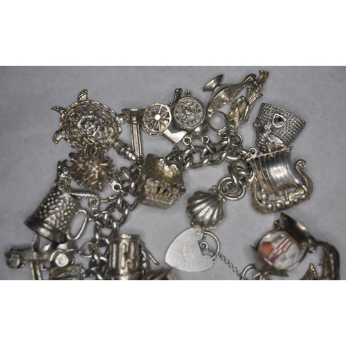 134 - SILVER CHARM BRACELET WITH 26 CHARMS AND HEART SHAPED LOCK AND SAFETY CHAIN 149.4g