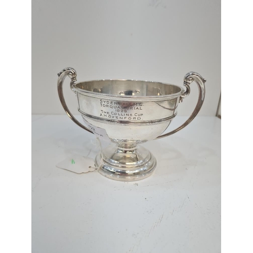 122 - A silver trophy cup on a raised pedestal circular base. Two handles with acanthus leaf detail. Bande... 