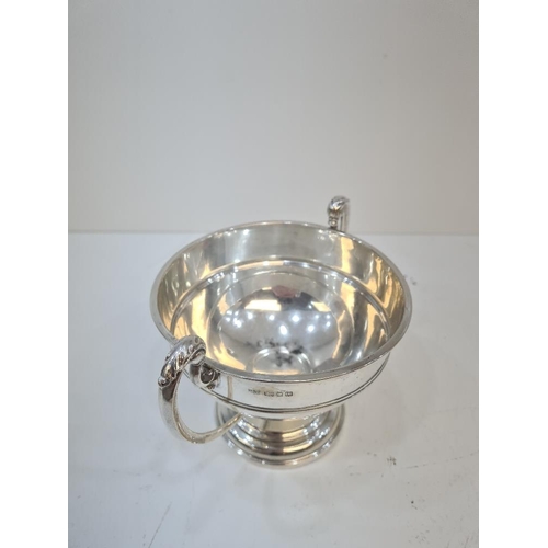 122 - A silver trophy cup on a raised pedestal circular base. Two handles with acanthus leaf detail. Bande... 