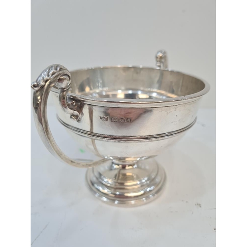 122 - A silver trophy cup on a raised pedestal circular base. Two handles with acanthus leaf detail. Bande... 