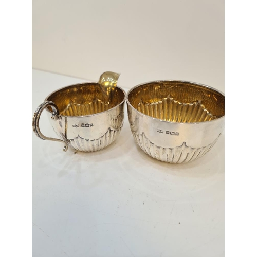 123 - A silver Edwardian Mappin and Webb sugar bowl and creamer, with gilt interior and half reeded body. ... 