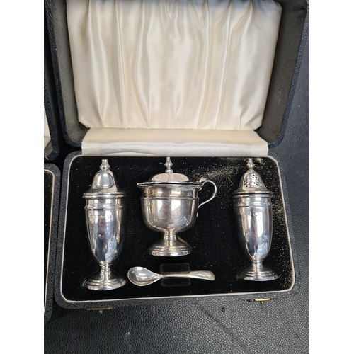 21 - A cased silver salt and pepper by W I Broadway and Co. With two cased Viners Ltd cruet sets. Total w... 