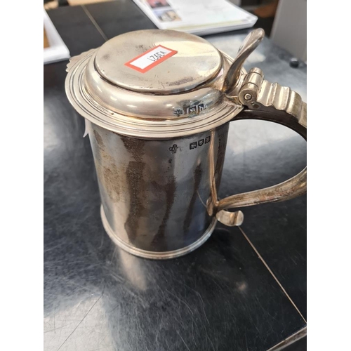 27 - A heavy silver tankard having hinged lid, bordered rims and scroll handle, with thumb piece. Cylindr... 