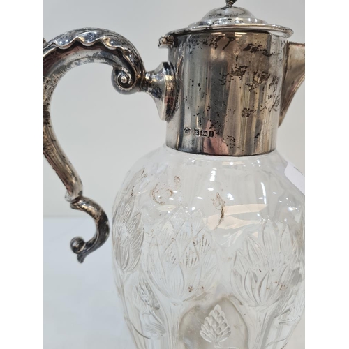 58 - A silver topped pretty cut glass Claret jug, having silver acanthus leaf scroll handle and flower em... 