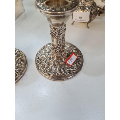 66 - A pair of decorative silver candlesticks, heavily embossed with foliate scrolls and a bird seated wi... 