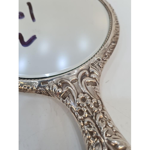 87 - A silver backed mirror, heavily embossed with angels, flowers and scrolls, by W I Broadway and Co. C... 