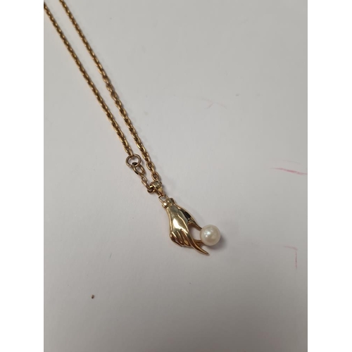 1064 - 9ct yellow gold neckchain, marked hung with a 14ct yellow gold pendant in the form of a hand holding... 