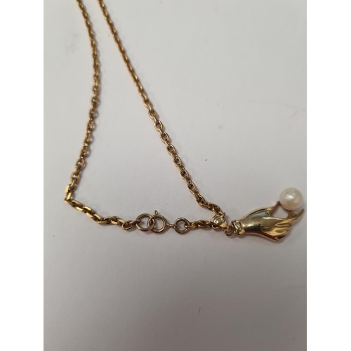 1064 - 9ct yellow gold neckchain, marked hung with a 14ct yellow gold pendant in the form of a hand holding... 