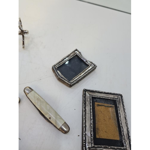 1127 - A mixed lot of silver and plated items to include a cased thimble, miniature silver frames, penknive... 