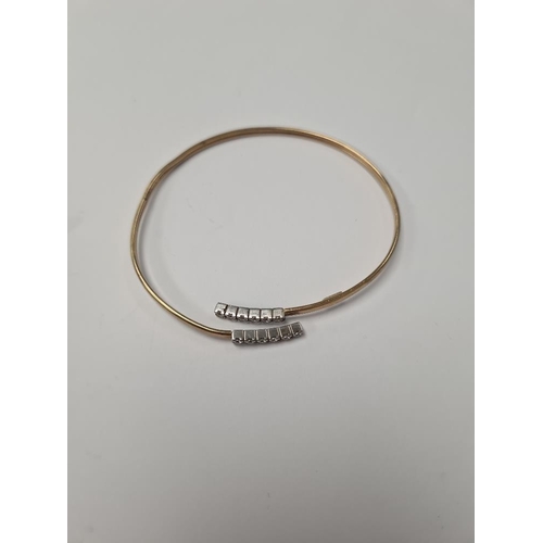 1052 - 9ct yellow gold open bangle, the ends each set with 6 cubic zirconias, marked 9ct, approx 3.9g