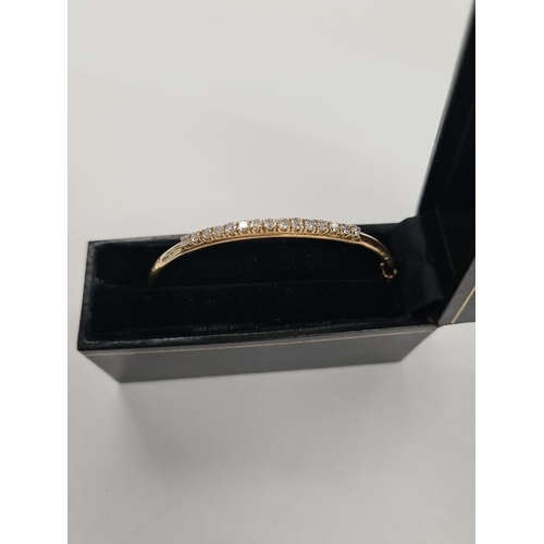 1123 - 18ct yellow gold hinged bangle the top set 15 round brilliant cut diamonds in 4 claw mounts, each ap... 