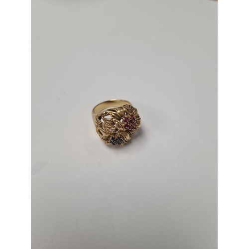 1073 - 18K yellow gold dress ring of decorative form, two flower heads, one inset rubies the other sapphire... 