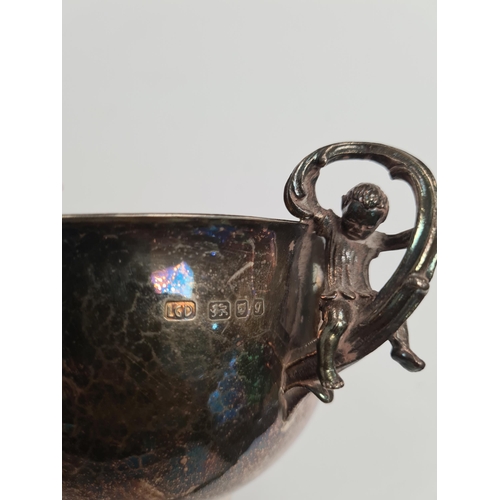 24 - An attractive silver two handled bowl with gilt interior. The handles each having a figure sat on a ... 