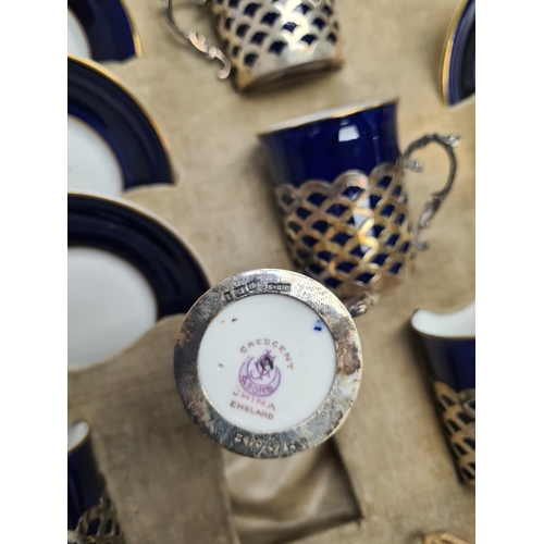 31 - A cased set of crescent china, the cups having silver pierced covers hallmarked Sheffield 1911, Jame... 