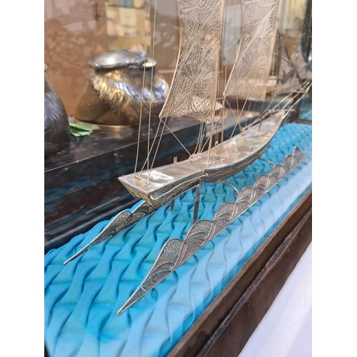52 - A filigree large boat in a case, having very intricate details, and ornate figures on the Sails. Att... 