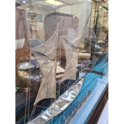 52 - A filigree large boat in a case, having very intricate details, and ornate figures on the Sails. Att... 