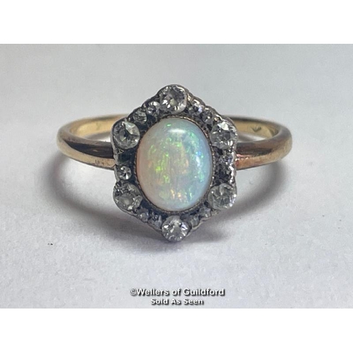 355 - Opal and diamond cluster ring. An oval opal surrounded by a border of old cut diamonds forming a hex... 