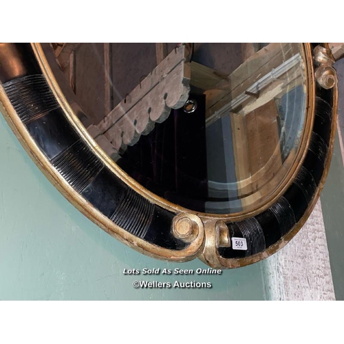 503 - PAIR OF 20TH CENTURY BLACK AND GILDED OVAL MIRRORS, 94 X 110CM (ONE MIRROR PLATE BROKEN)