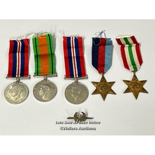 314 - Four medals including the Italy star and the 1939-1945 star with a military cap badge stamped Silver... 