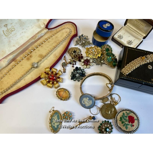 334 - Bag of assorted costume jewellery, mostly brooches, a hinged bangle stamped gold on silver, a gold p... 