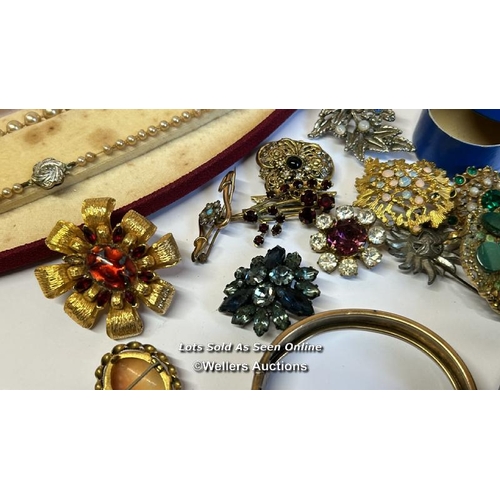 334 - Bag of assorted costume jewellery, mostly brooches, a hinged bangle stamped gold on silver, a gold p... 