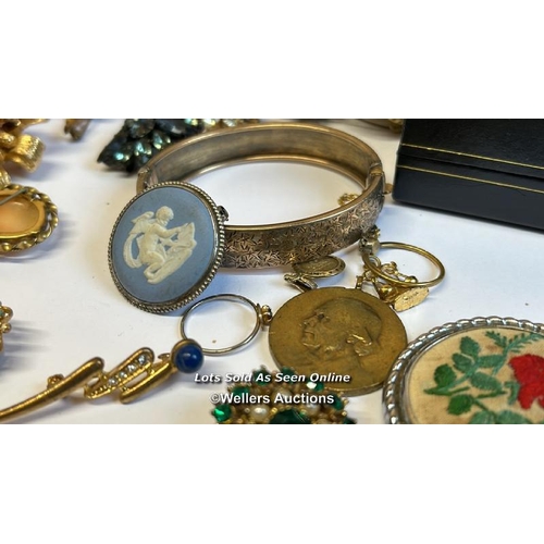 334 - Bag of assorted costume jewellery, mostly brooches, a hinged bangle stamped gold on silver, a gold p... 