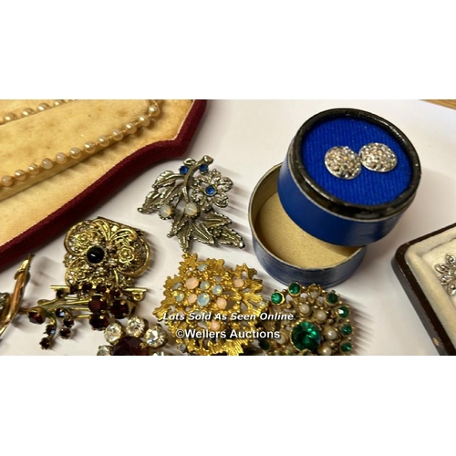 334 - Bag of assorted costume jewellery, mostly brooches, a hinged bangle stamped gold on silver, a gold p... 