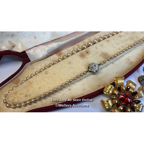 334 - Bag of assorted costume jewellery, mostly brooches, a hinged bangle stamped gold on silver, a gold p... 