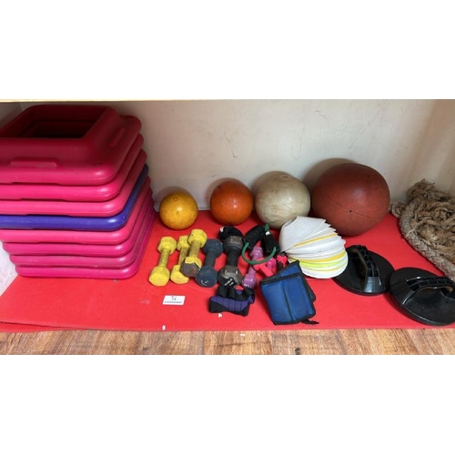 74 - A SHELF OF EXERCISE ITEMS INCL. ASSORTED DUMBELLS, CONES, MEDICINE BALLS ETC.