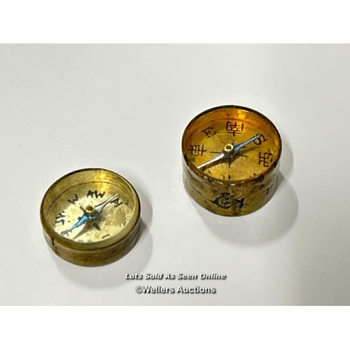 76 - Two very small brass compasses, both 1.5cm diameter. One has Chinese numerals with a printed clock o... 